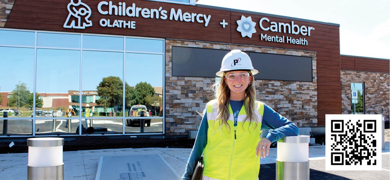 young woman in hard hat and vest in front of Olathe Mental Wellness Campus