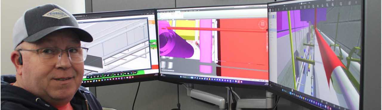 Plumbing BIM detailer in front of three monitors showing building information modeling drawings