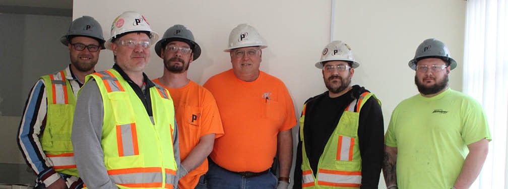 P1 Construction mechanical construction team, six construction workers wearing safety vests, high viz shirts, and hard hats